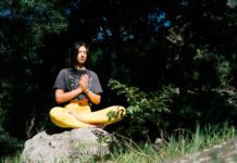 Mindfulness in Everyday Life: Finding Peace in the Chaos photo of woman doing yoga while sitting on rock