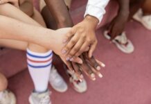 The Importance of Community: Surrounding Yourself with Motivational Influences faceless multiracial sport team stacking hands on court