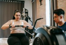 Motivation Psychology a personal trainer next to a woman exercising on rowing machine