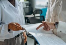 Motivation Theories in Management colleagues standing in white long sleeve shirts discussing and reading a financial report