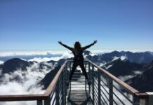 What is Life Personal Development? person standing on hand rails with arms wide open facing the mountains and clouds